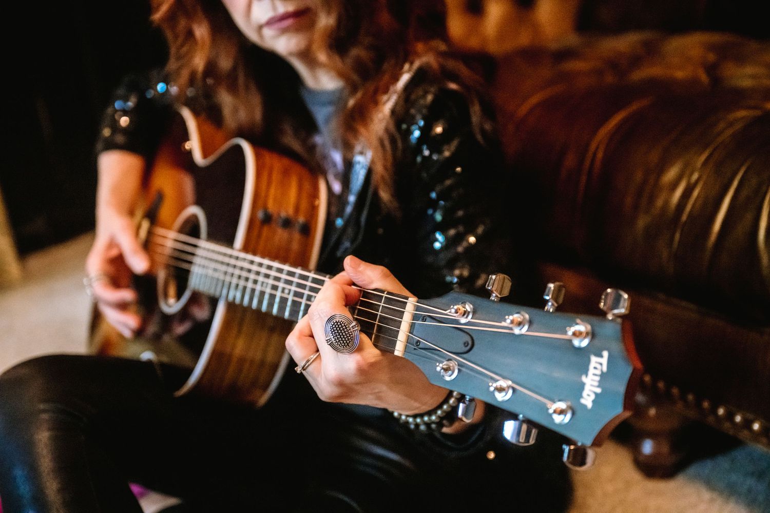 Close-up details of acoustic guitar being played in warm lighting.