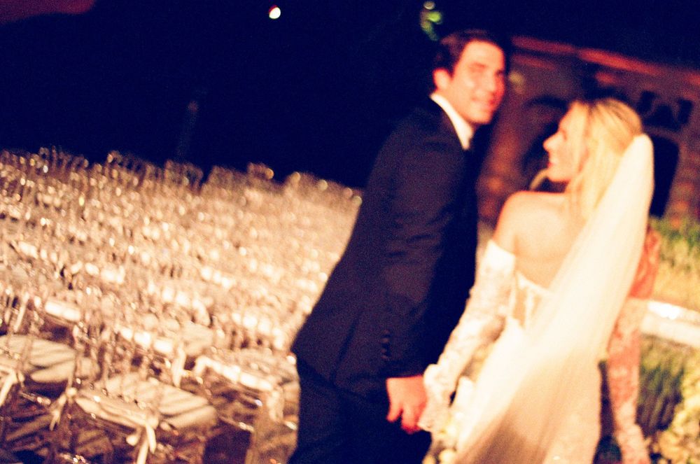 Beautiful ice sculptures glowing with colorful lights illuminate an elegant outdoor nighttime wedding reception.