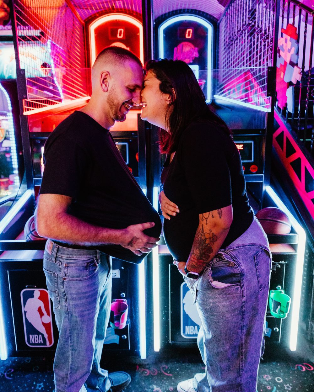 Couple sharing a romantic moment at an NBA arcade basketball game, glowing neon lights in the background.