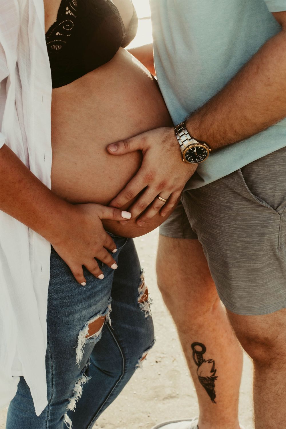 Close up of a couple holding hands on the beach.