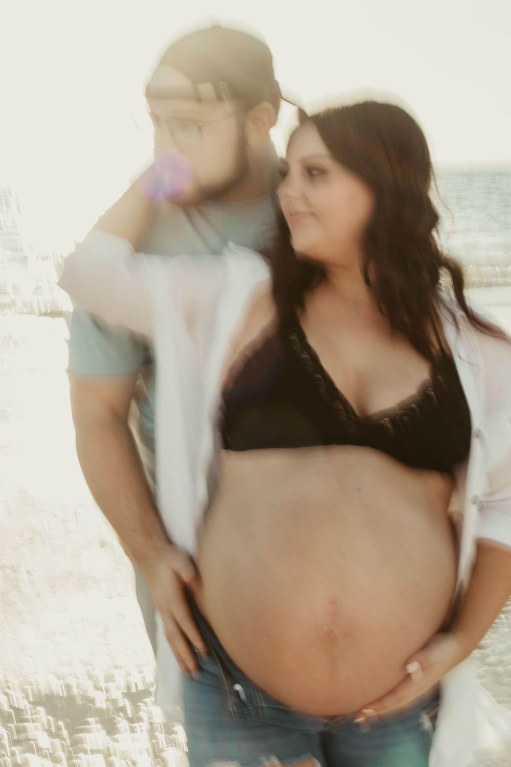 A couple embraces intimately on a bright sunlit beach.