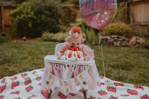 Pink smash cake photoshoot setup in a garden with watermelon decorations shows first birthday celebration preparations.