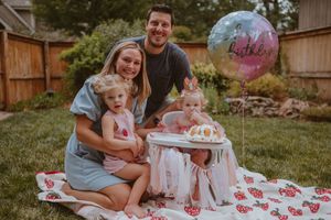 Children celebrating at a summer birthday party with cake and outdoor decorations on a table with floral tablecloth.