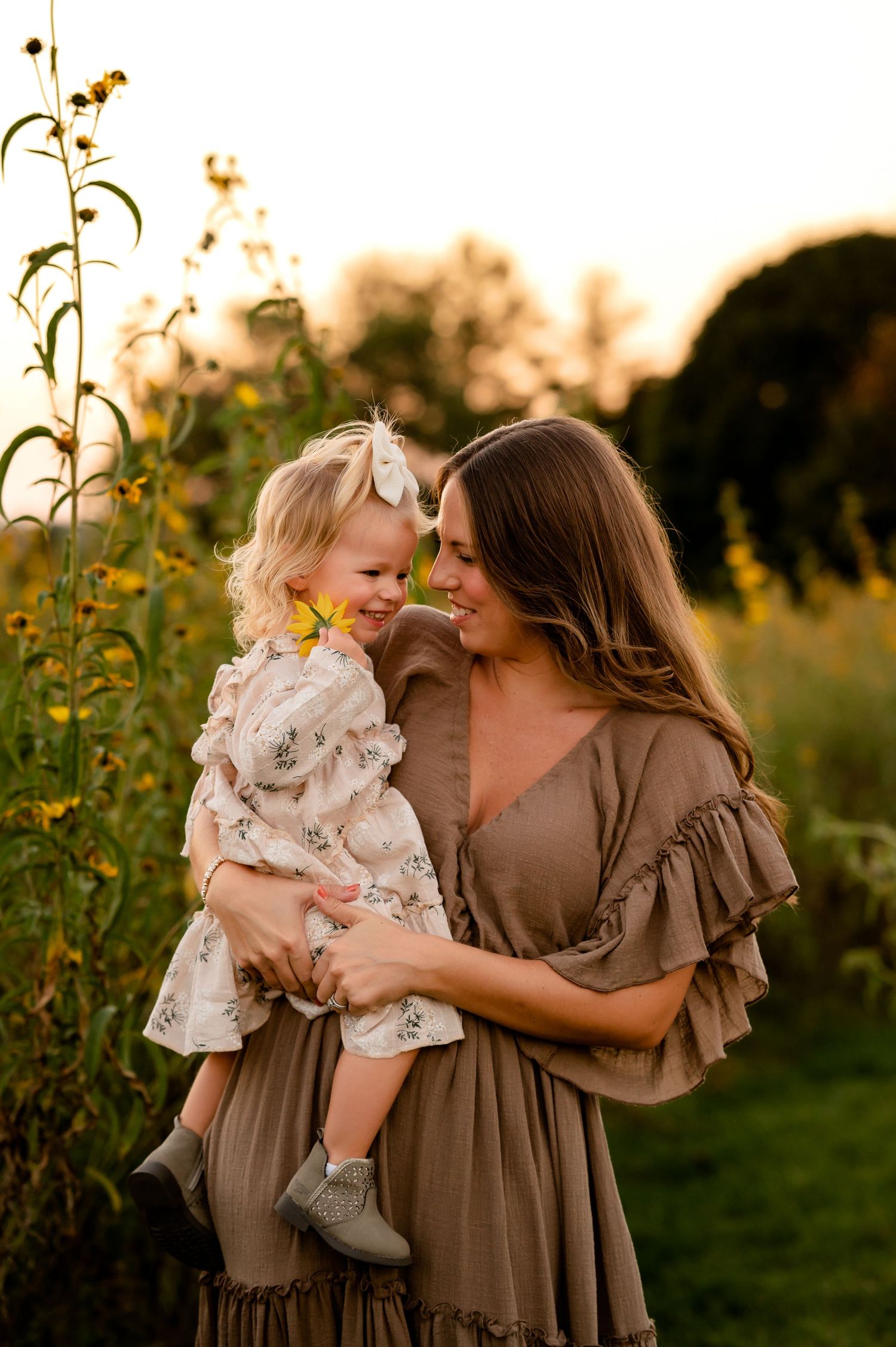 Mother holding daughter in a golden sunlit field at sunset created by Storms Photography in Pennsylvania.