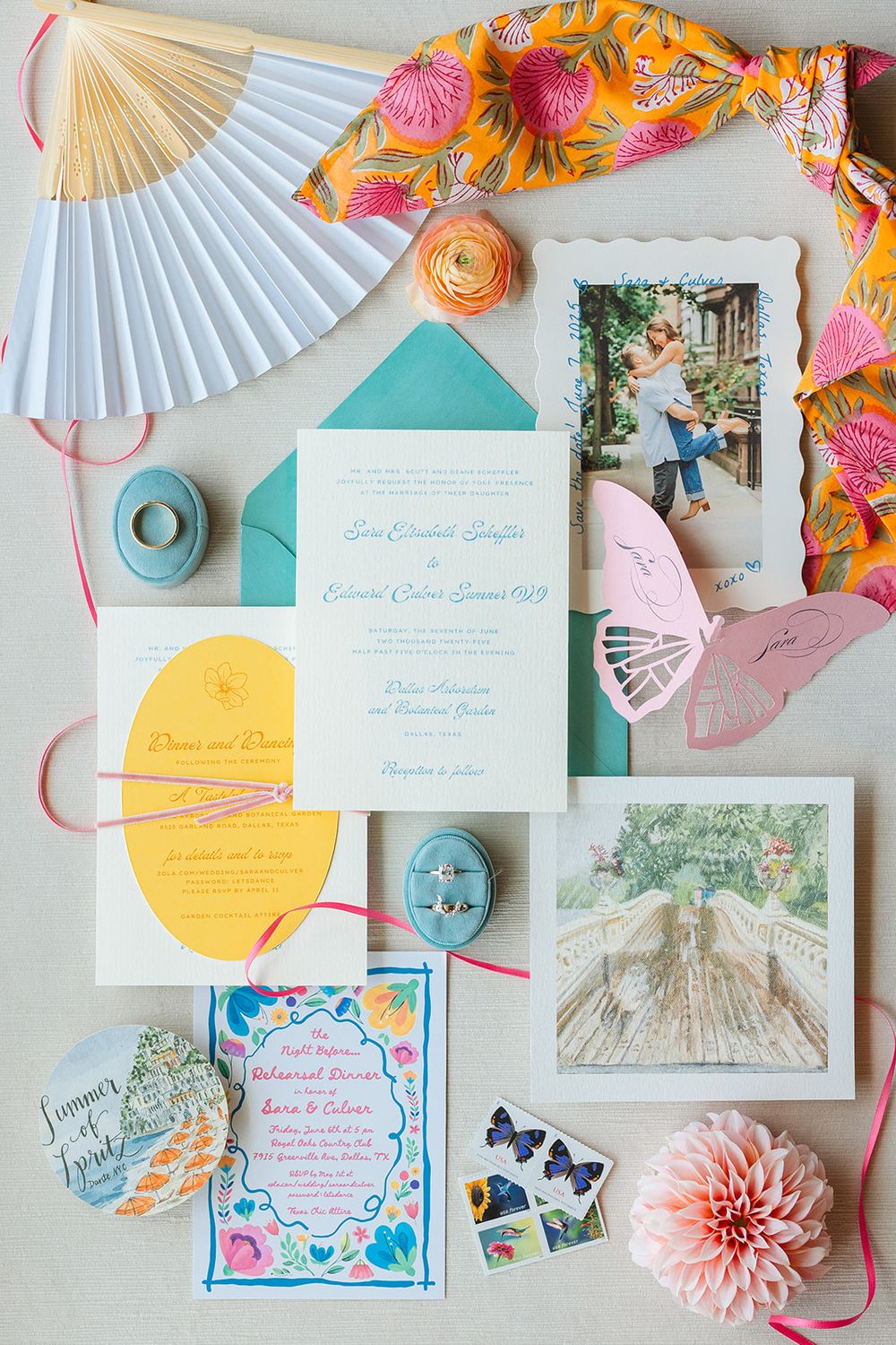 Colorful wedding invitation suite with paper fans, floral designs, and turquoise accents displayed on white background.