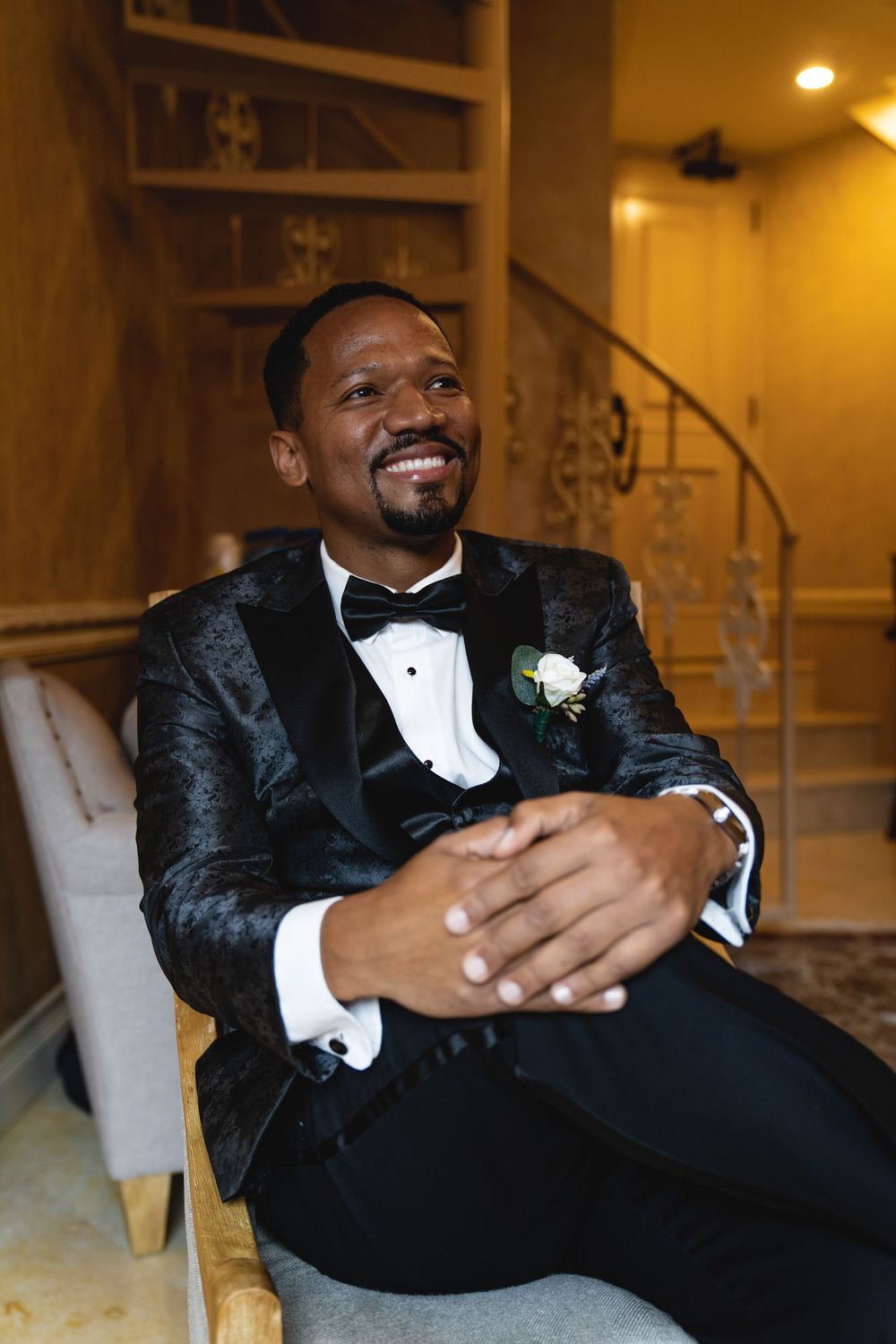 Men in formal attire relaxing on chair showing emotions during wedding day.