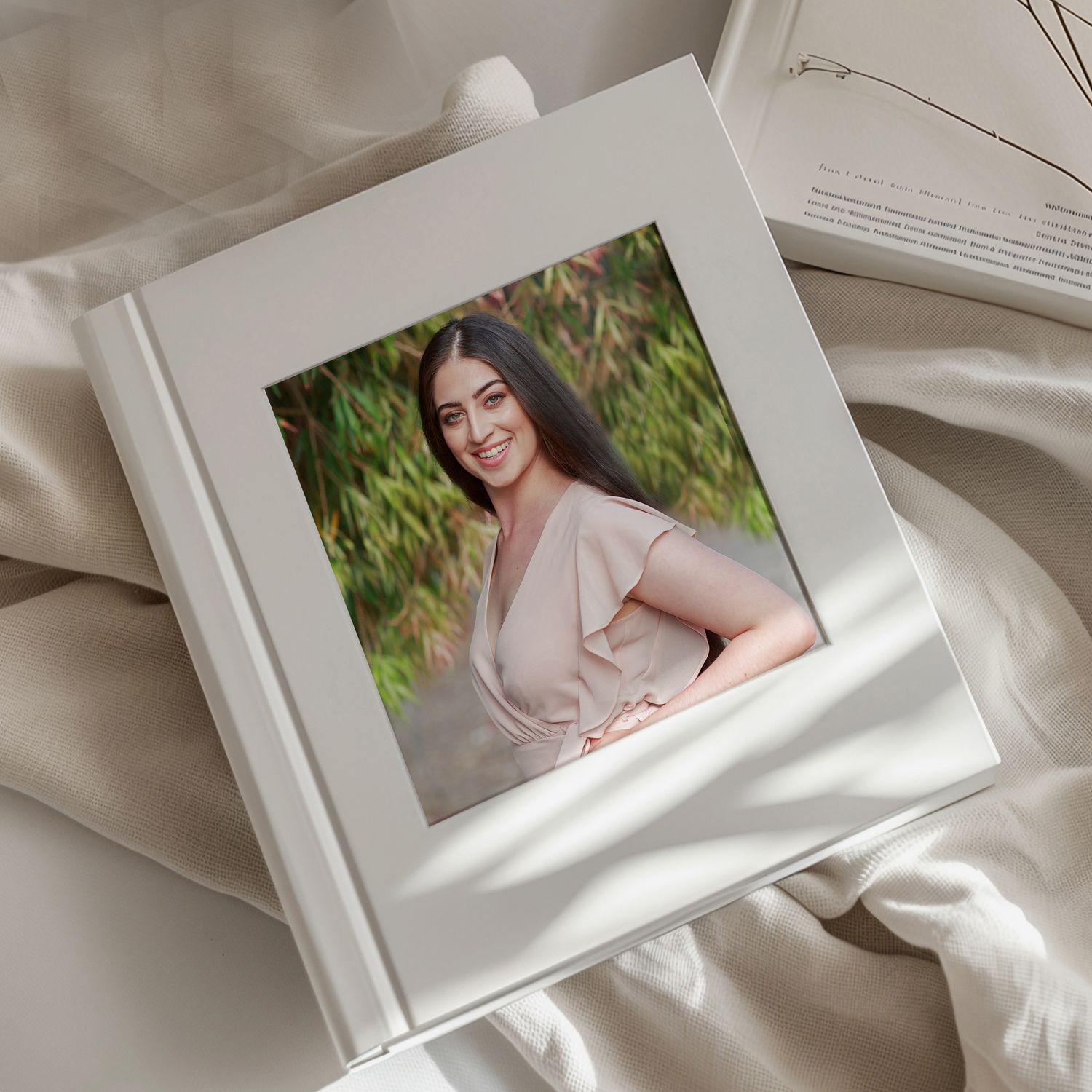 Multiple white photo prints arranged in an elegant layout on textured white fabric with soft shadows and ethereal lighting.
