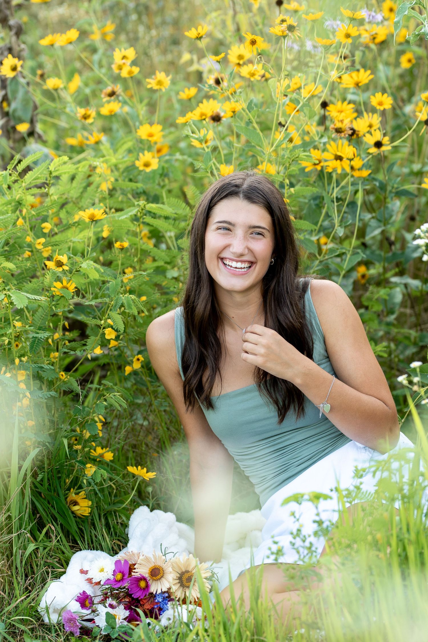 Joyful outdoor portraits of a person sitting in a field of vibrant yellow wildflowers and purple blooms.