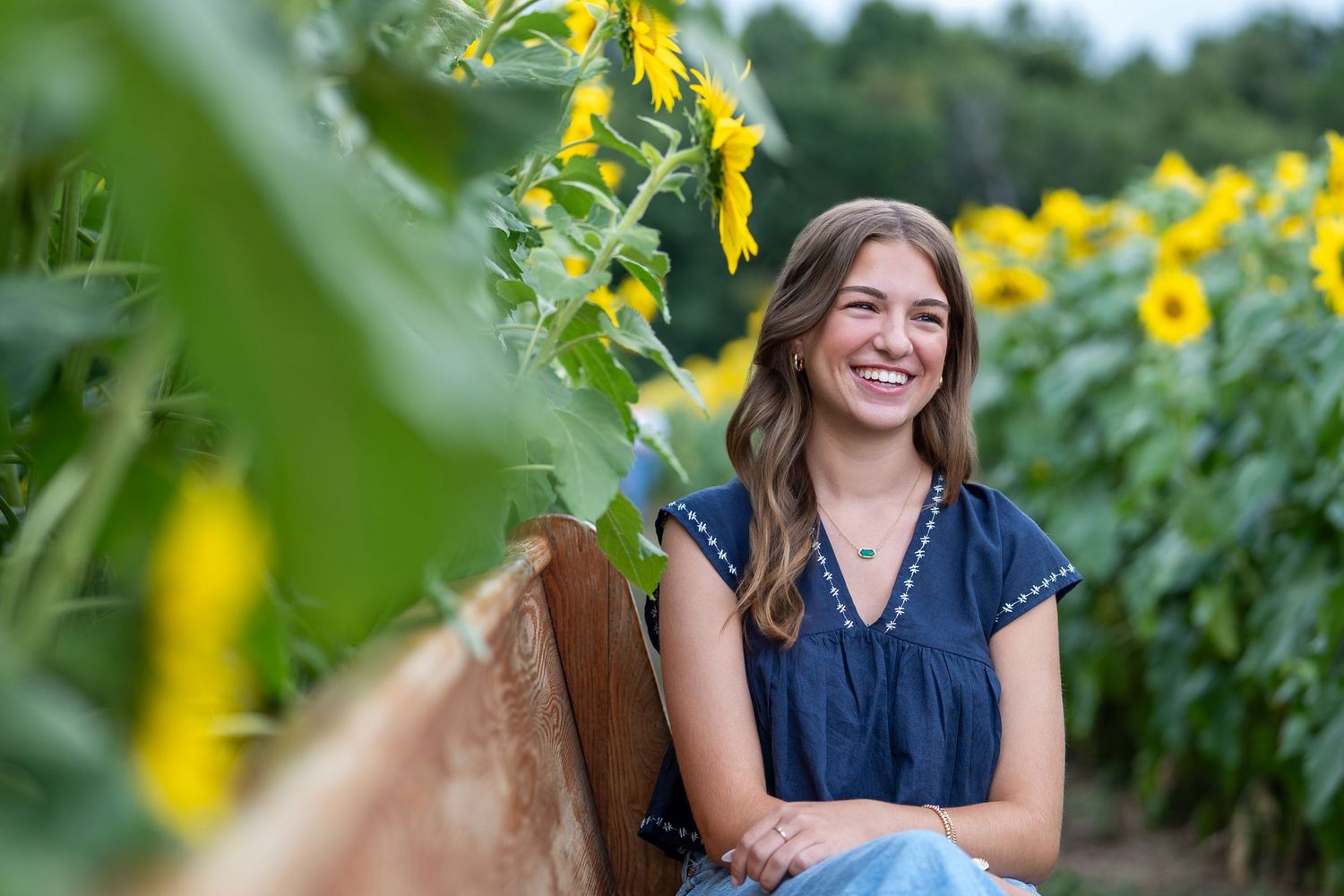 A person poses cheerfully in a vibrant sunflower field on a bright summer day.