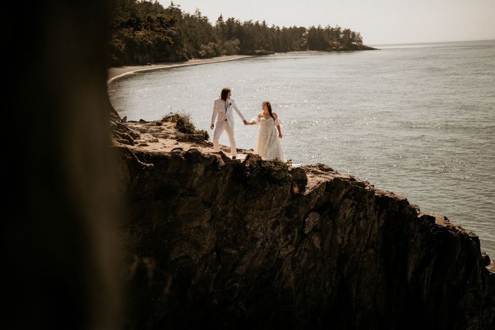 Wedding couple walking up the side of a cliff at Deception Pass. Photo captured by drone.
