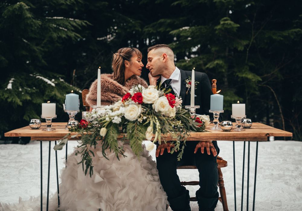 Bride and groom share a kiss at their table in the snow at Gold Creek Pond in Washington after they eloped.