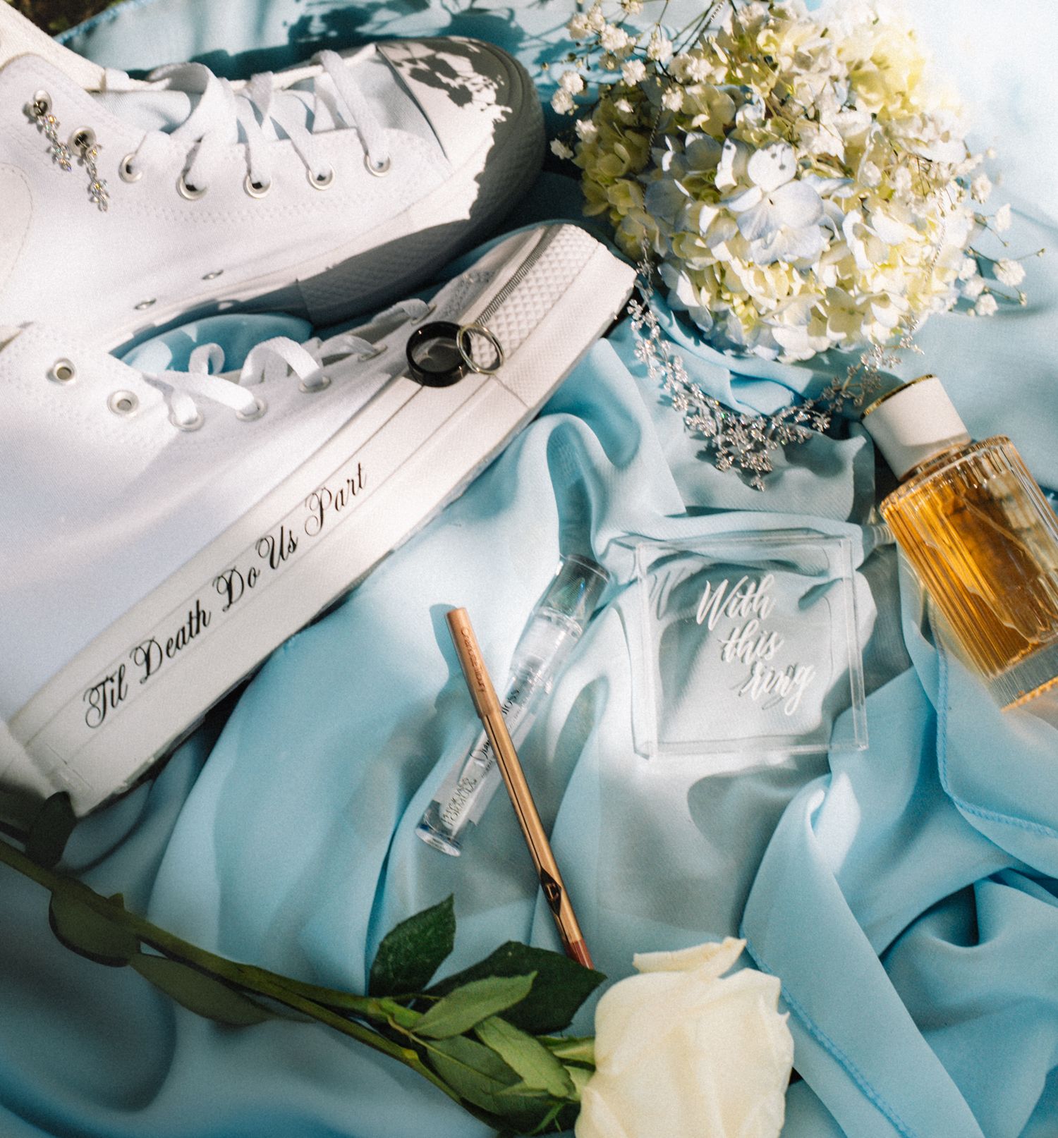 Wedding detail shot featuring light blue fabric, white flowers and delicate decor elements.