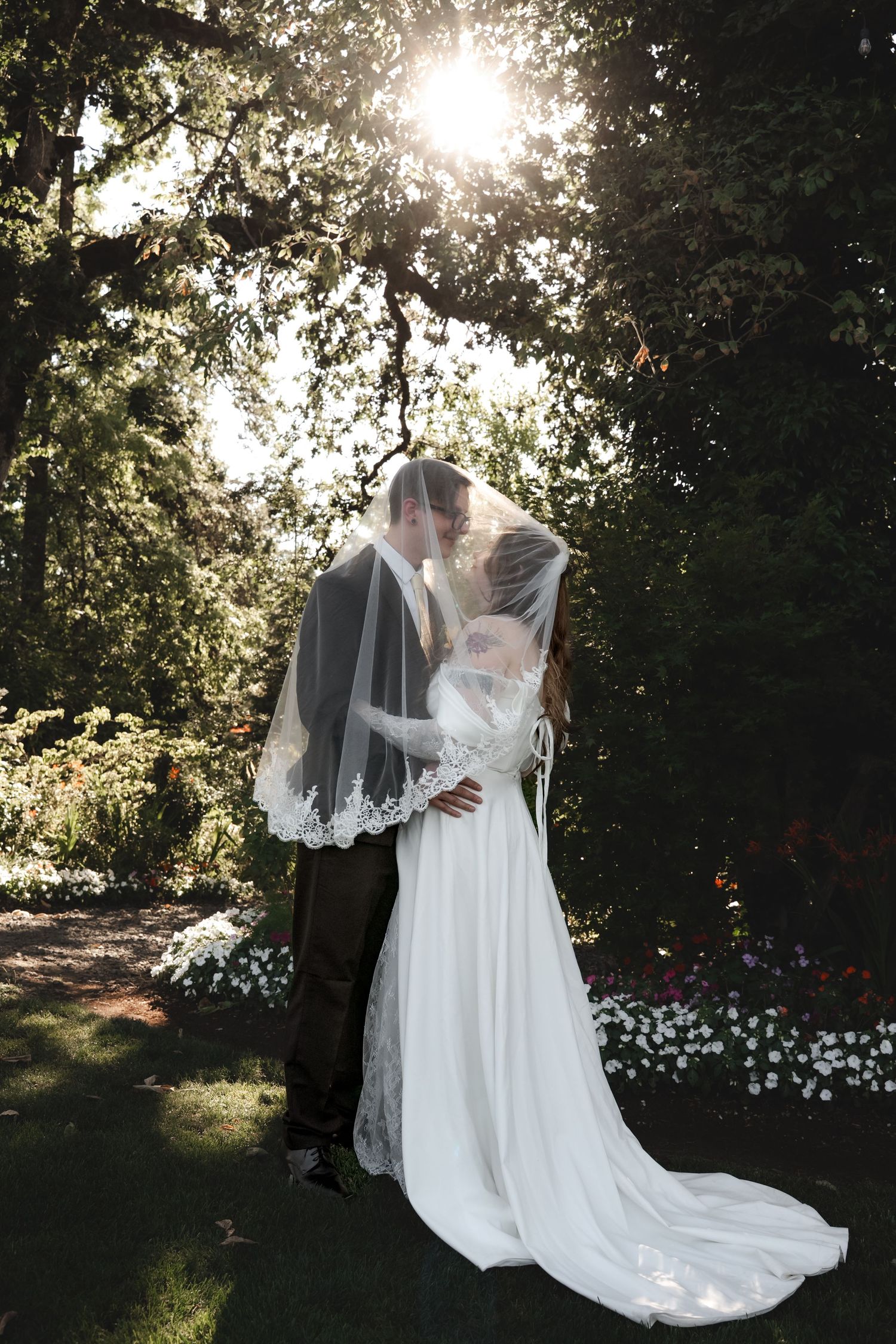 A sunlit wedding photoshoot with flowing white dress in a garden setting.