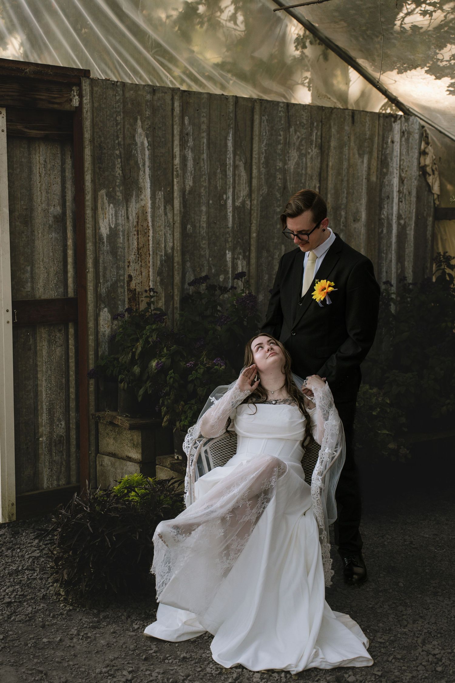 A wedding couple poses against a rustic wooden fence backdrop.
