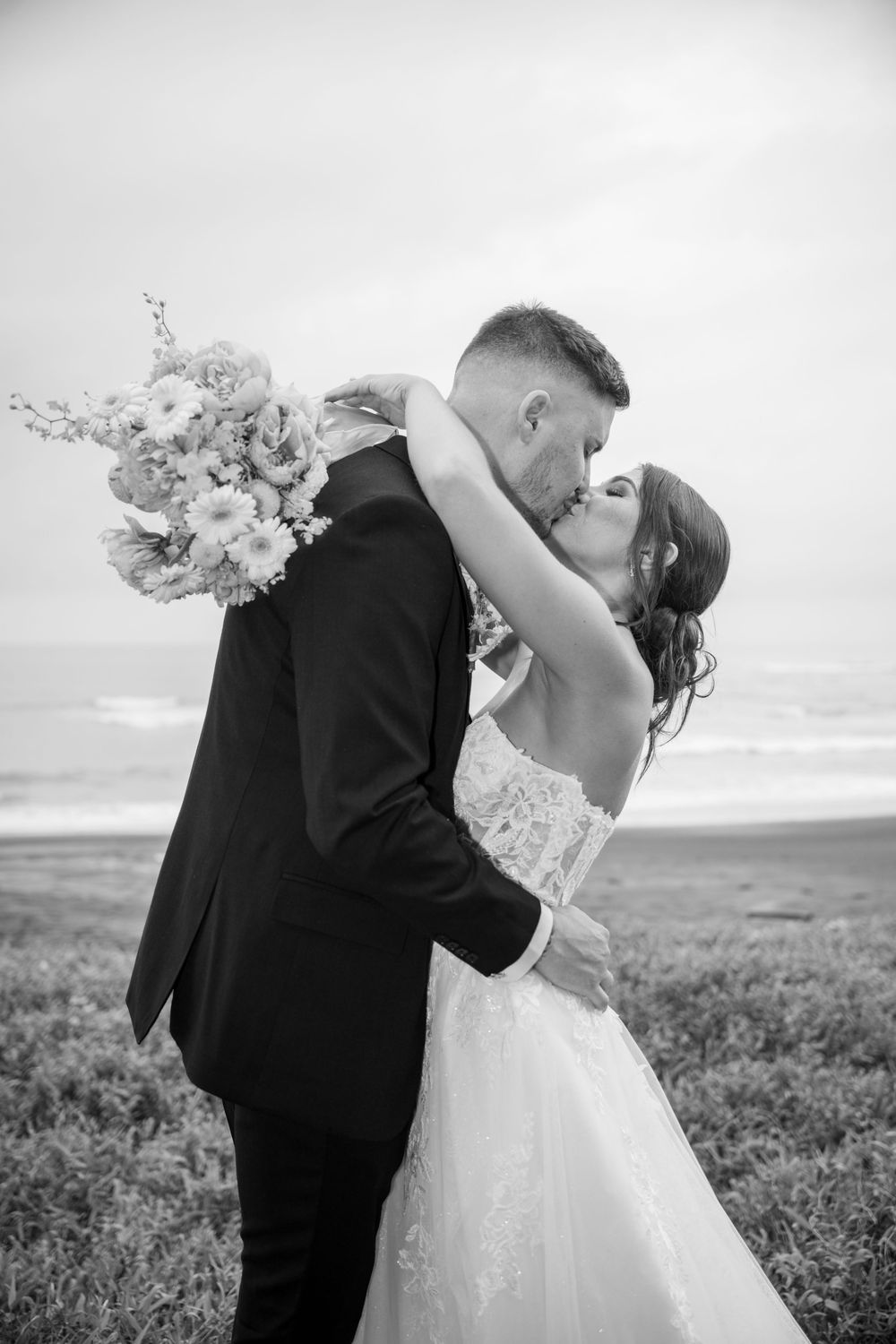 A romantic black and white wedding photo series showing a couple embracing on a hilltop overlooking a scenic landscape.