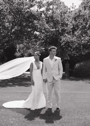 A romantic black and white wedding photo of a couple on a lawn with the bride's veil flowing in the breeze.