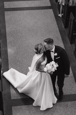 Overhead view of a bride in a flowing white dress holding a bouquet while sharing an intimate moment on their wedding day.