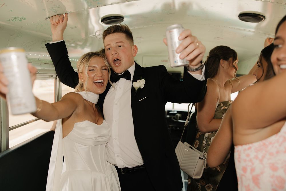 Wedding reception guests dancing and raising glasses in celebration on a festive dance floor.