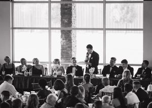 A black and white photograph of people dining in a bright restaurant with large windows and a modern interior.