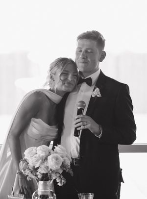 A black and white wedding moment captured of a bride and groom sharing an intimate speech at their reception.