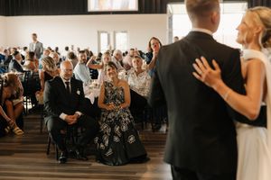 Wedding guests watch as newlyweds share their first dance in a rustic indoor venue.