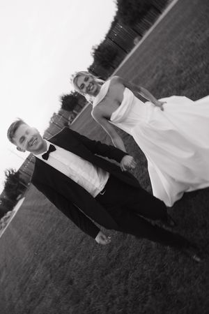 A black and white photo of a couple on their wedding day, walking together outdoors.