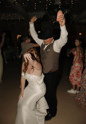 Couple dancing together at their wedding reception under dimly lit romantic lighting.