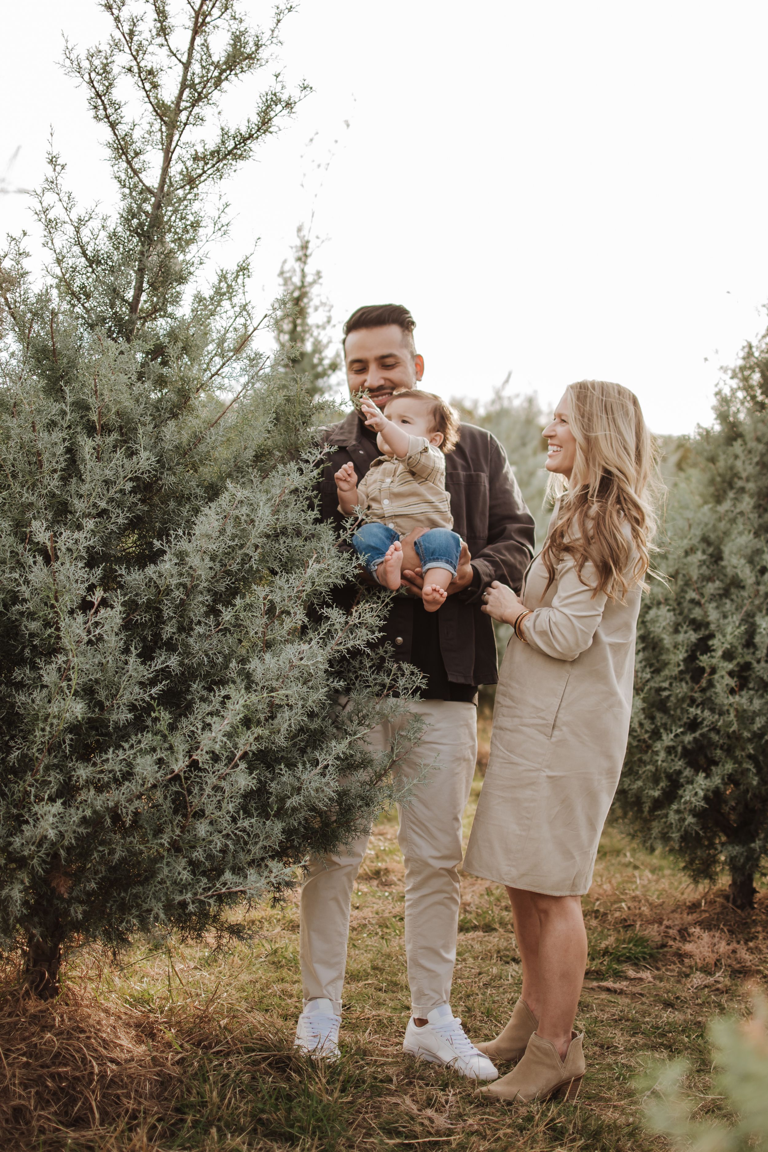Holiday mini session with warm outfits and evergreen backdrop near Fort Worth