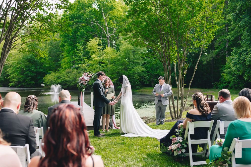 Outdoor wedding ceremony setup with rows of chairs in a lush green garden setting.
