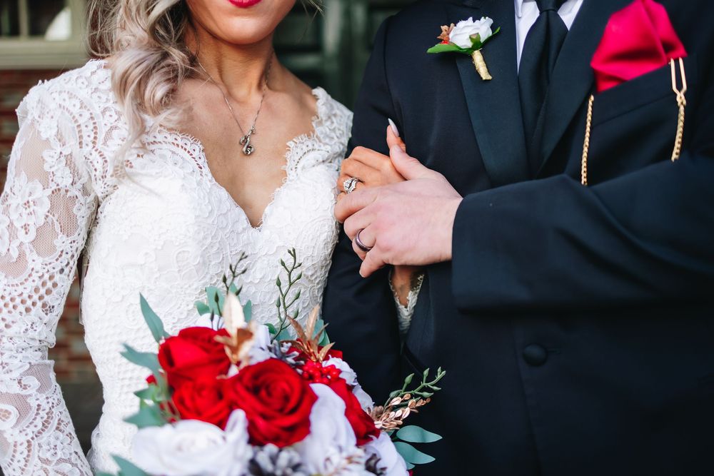 Close-up details of wedding attire with red roses and lace elements.