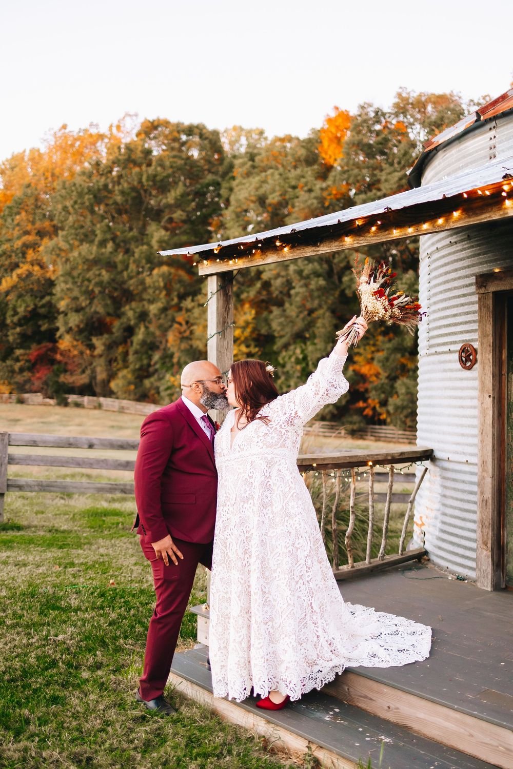 Couple poses playfully in front of a rustic building during their wedding photoshoot.