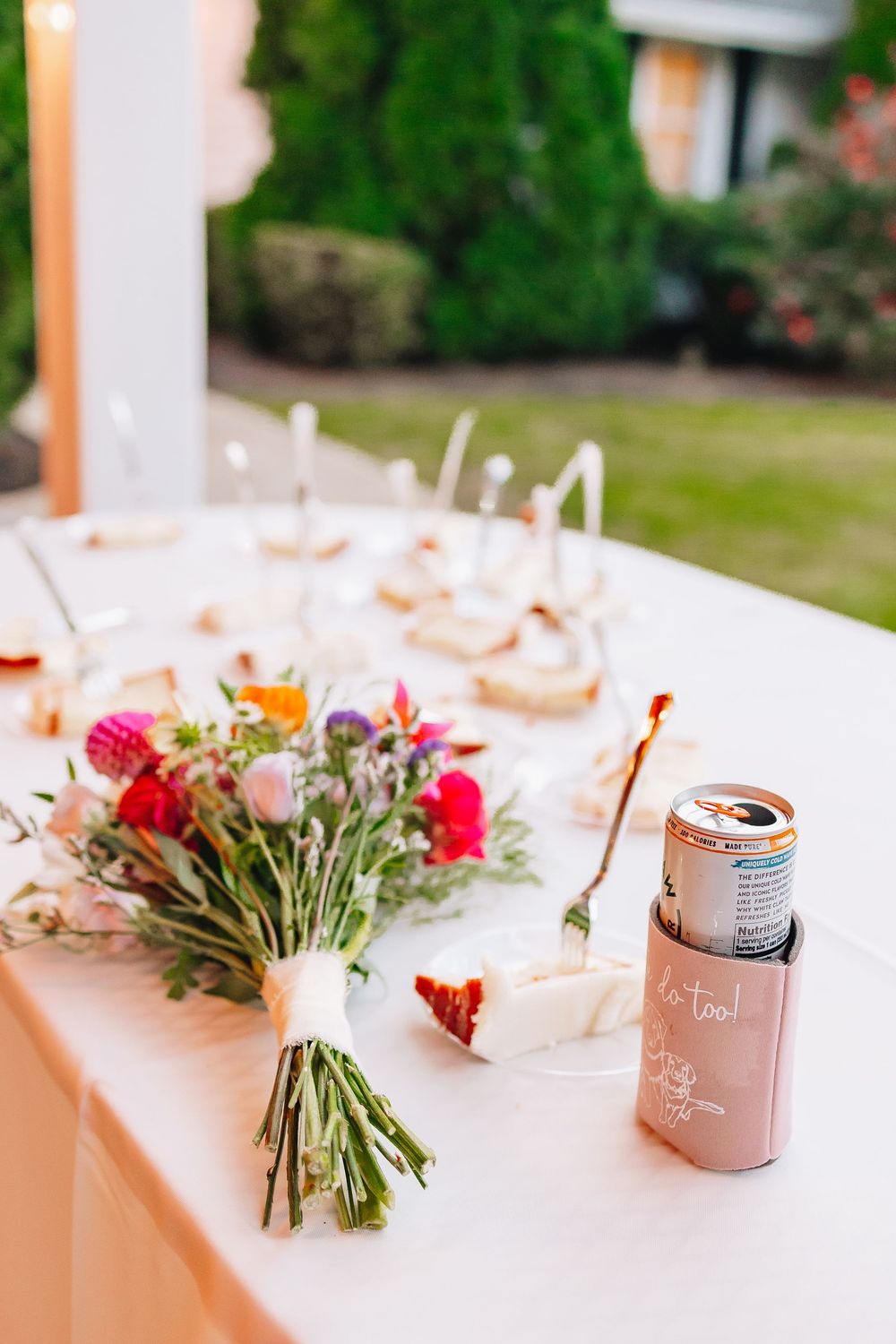Wedding reception table decorated with loose floral arrangements and rose gold drink cans.
