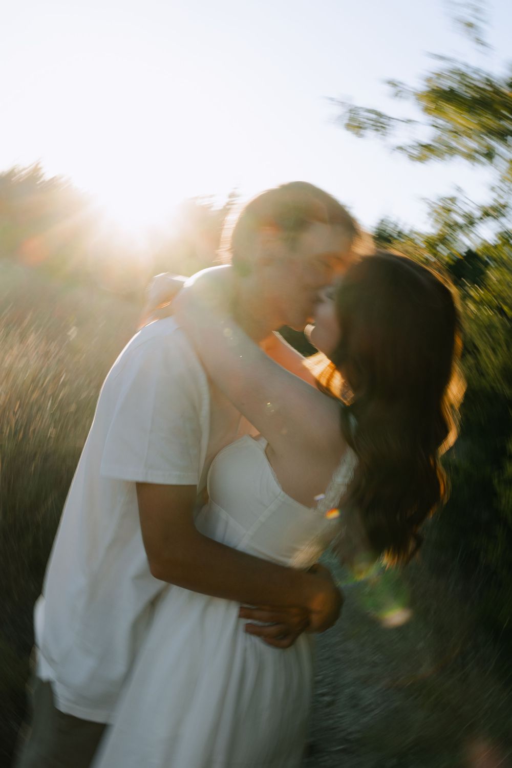 A romantic sunset moment captured between two people in an outdoor setting with golden light.