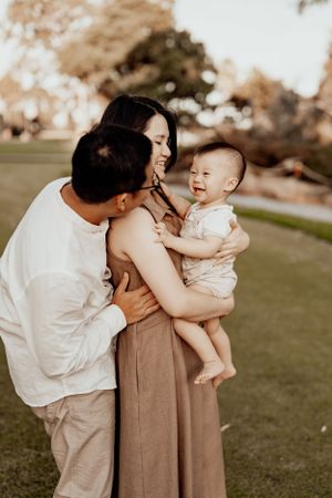 Family photoshoot on grassy lawn during golden hour showing loving interactions.