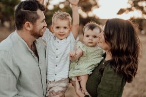 Candid family portrait in neutral tones against sunset backdrop.