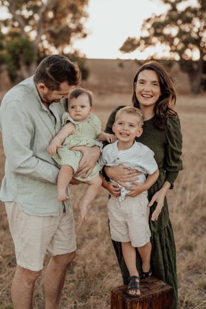 Family enjoying playful moments together in a golden sunset field.