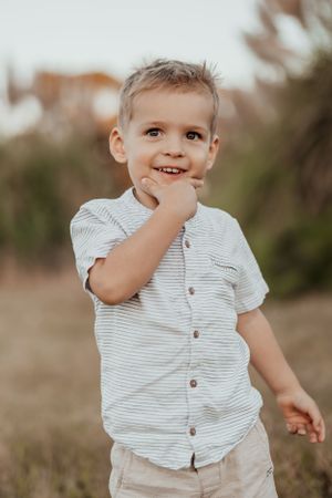 Young child in striped shirt playing outdoors with joyful expression.