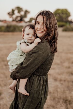 Mother and child share tender moments in olive green dress during outdoor portrait session.