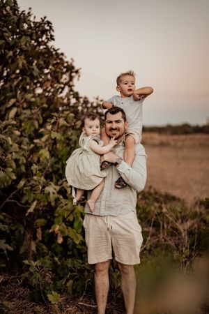 Happy family plays and laughs together during outdoor photo session at sunset.