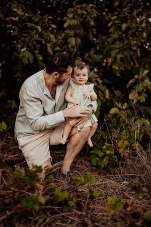Intimate family moment captured in natural outdoor setting among foliage.