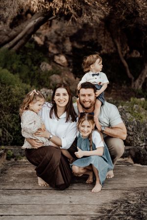 Family members cuddled together on wooden platform outdoors.