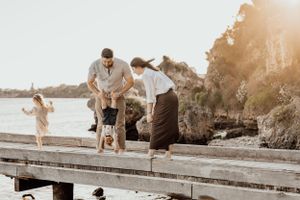 Family enjoying playful moment together on wooden dock by the sea.