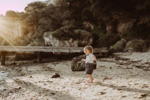 Children playing and exploring on a rocky beach landscape.