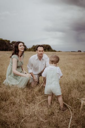 A family shares a playful moment together in a golden field during sunset.