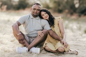 A couple lounges on soft grass during an intimate outdoor photo session.