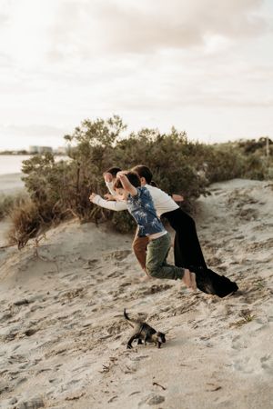 Playful moments captured on sandy dunes with people running and jumping together.