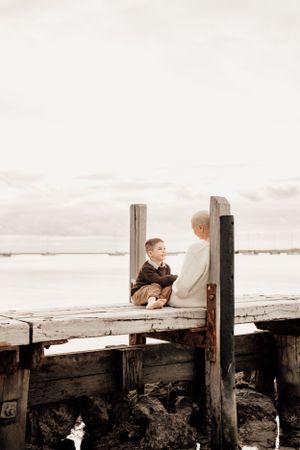Quiet conversation on rustic wooden pier overlooking calm waters.