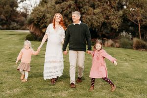 Family walking together through a green field during golden hour.