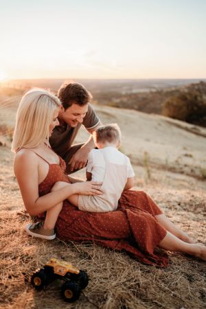 A family shares an intimate moment on a hillside during golden hour.
