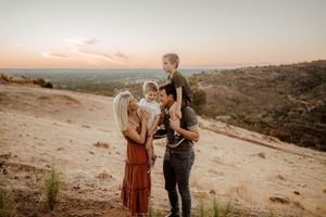 A romantic sunset photoshoot captures a couple against a desert landscape backdrop.